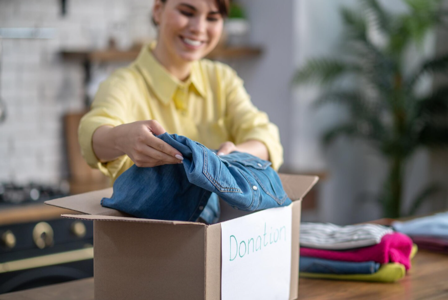 Adding clothes to donation box for year-round closet decluttering