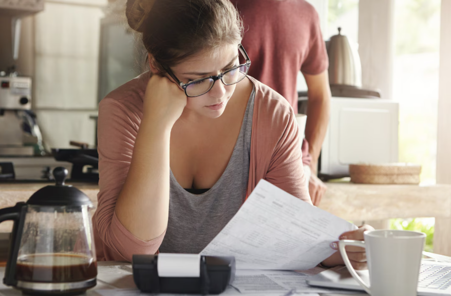Person reviewing bills at kitchen table to identify hidden fees in everyday services