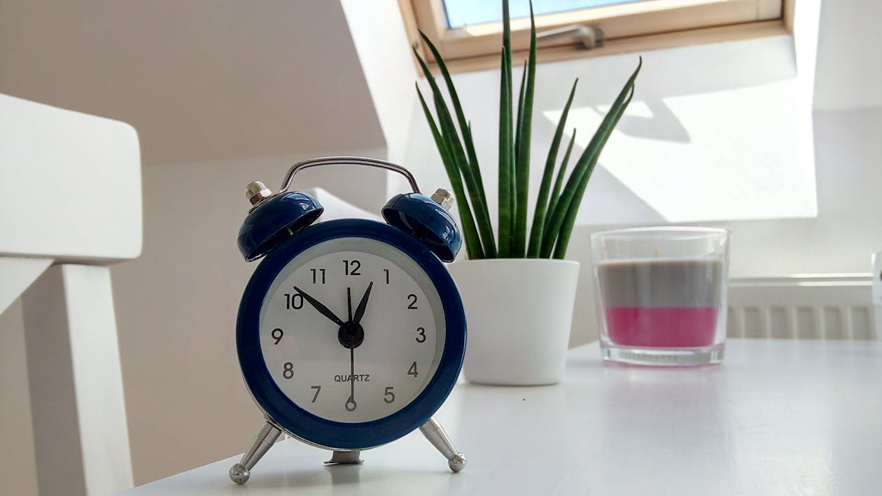 Blue alarm clock on white desk representing a weekly home reset routine